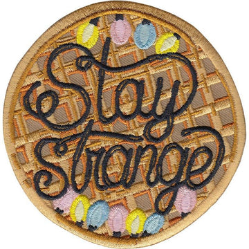 STAY STRANGE Strygemærke, en vaffel med sirup, farver og teksten STAY STRANGE