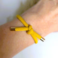 OKKERGUL Hårelastik og armbånd båret som armbånd om håndleddet.