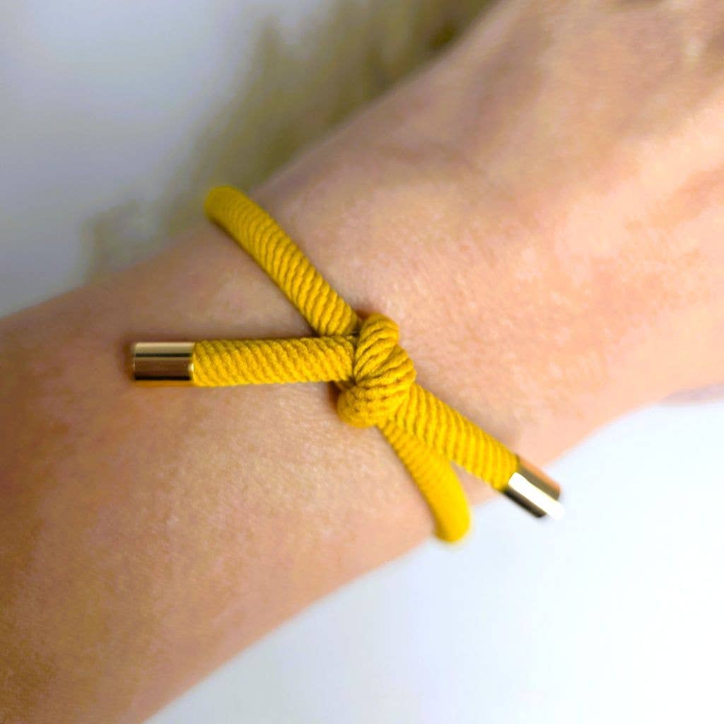 OKKERGUL Hårelastik og armbånd båret som armbånd om håndleddet.